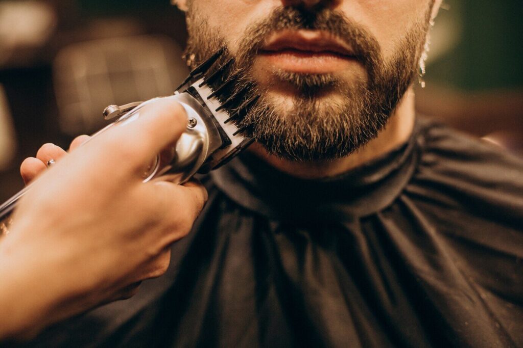Foto detalle de un cliente al que le están retocando la barba
