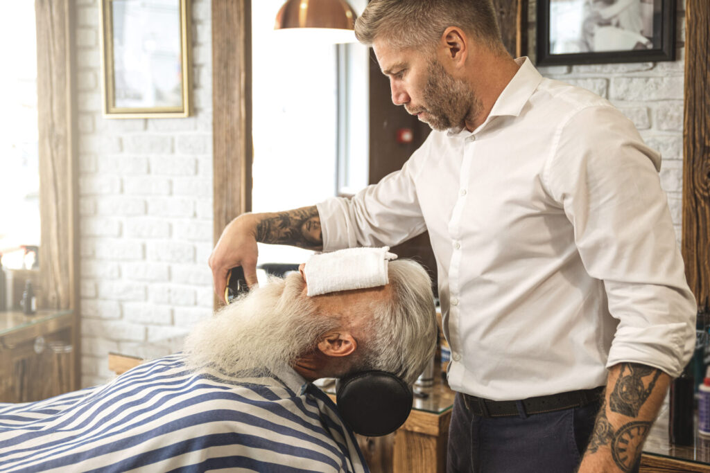 Handsome senior man getting styling and trimming of his beard