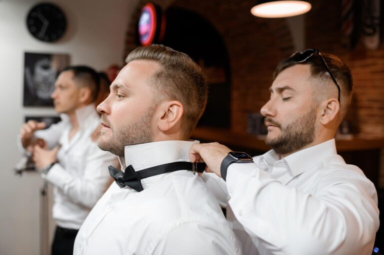 Vista lateral novio confiado barba bigotes pie mirando otro lado mientras su amigo esta detras el lo ayuda vestirse camisa corbata mono habitacion hotel dia boda 8353 12417
