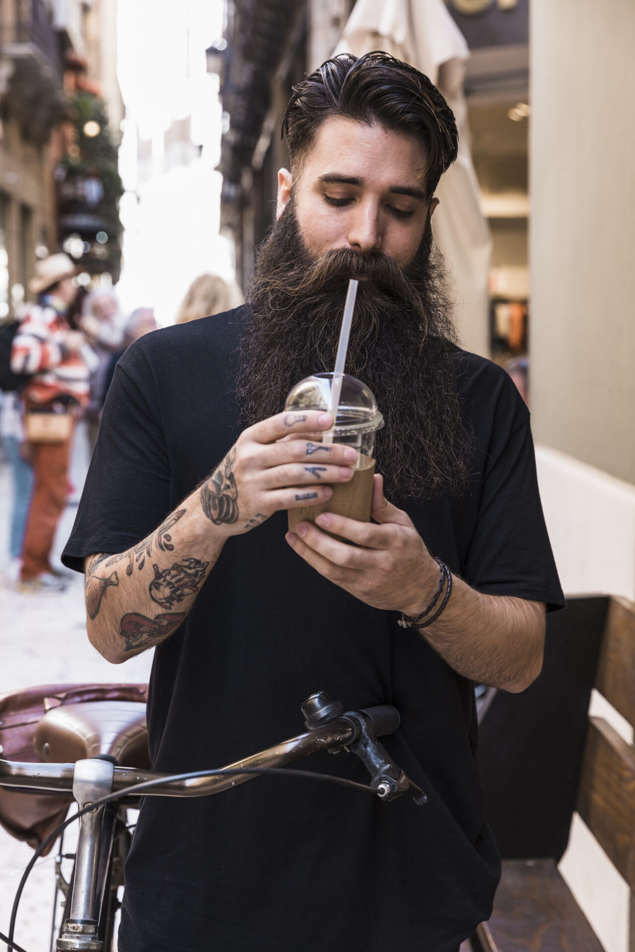 bebida-del-chocolate-de-consumicion-del-hombre-barbudo-que-se-coloca-con-la-bicicleta-en-la-calle-de-la-ciudad Foto del barbero Zakariae