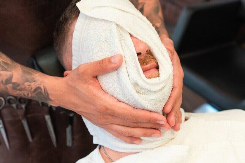 Disparo vertical peluquero masajeando rostro joven cliente envuelto toalla barberia 181624 53211